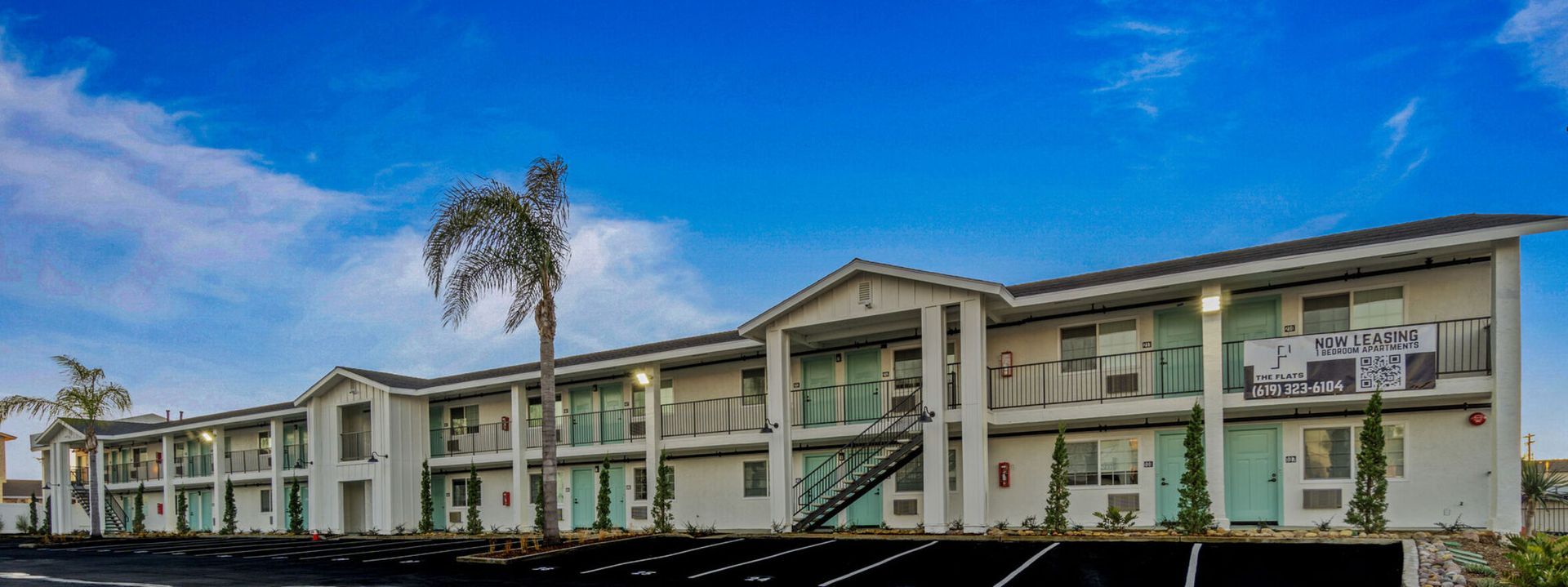 Photo of a two story building with a palm tree in front of it