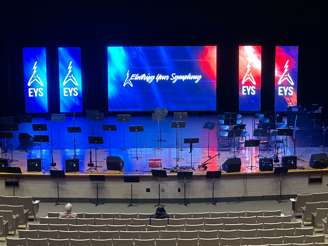 An empty auditorium with a large screen that says eys on it