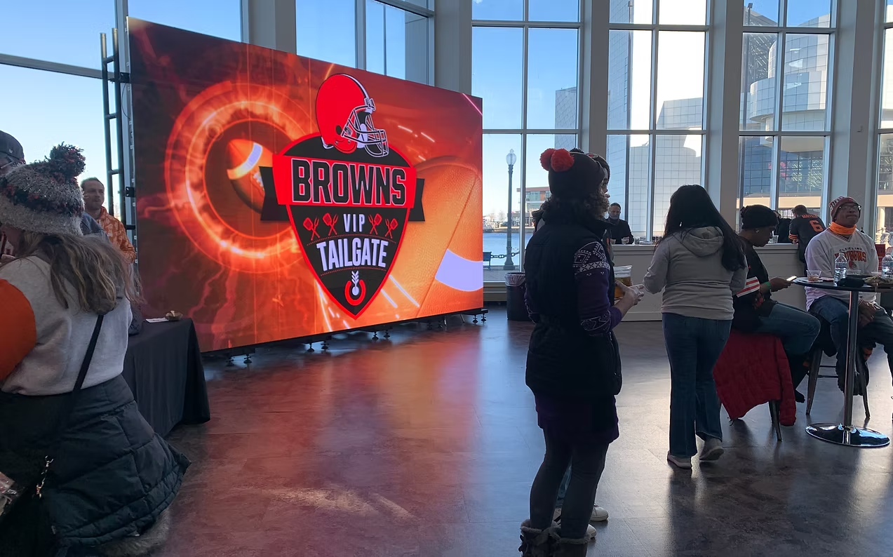 A group of people are standing in front of a large screen.