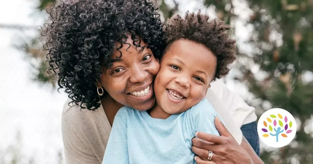 Smiling woman hugging a smiling child outdoors