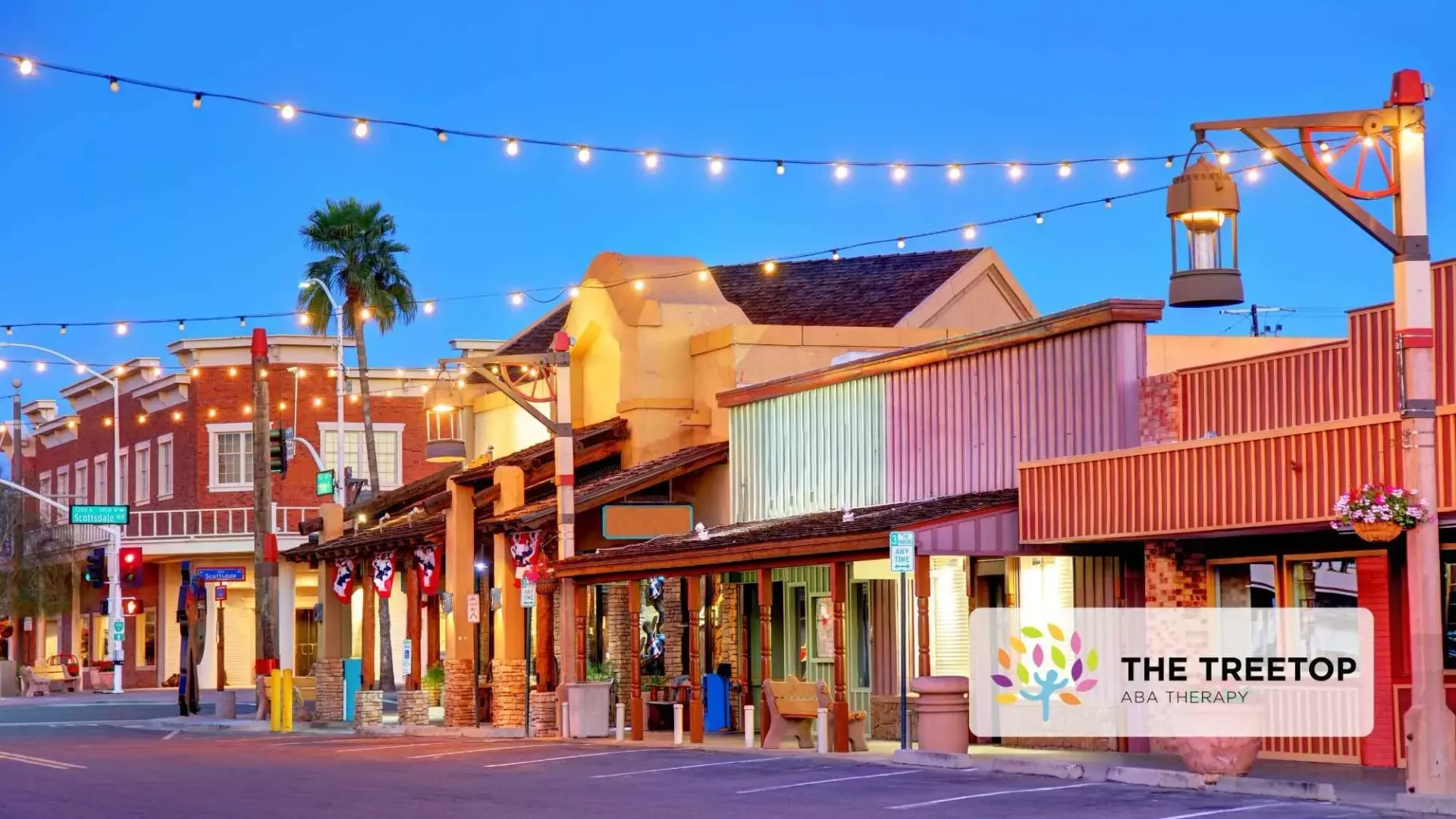 Colorful historic street at dusk with lit storefronts and palm trees, The Treetop sign visible.