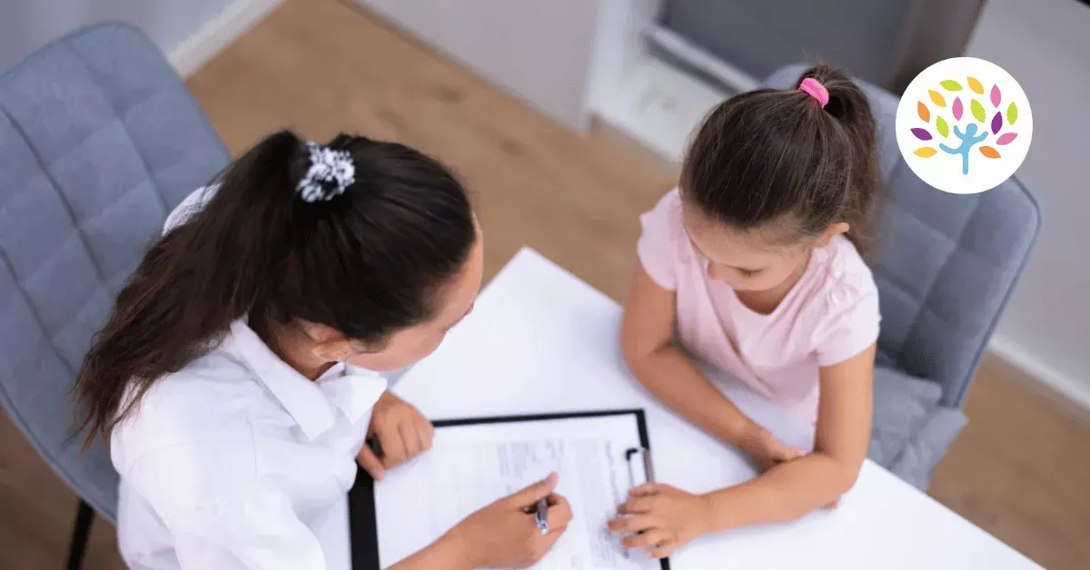 A professional sitting at a table with a child, reviewing a document together in an office setting.