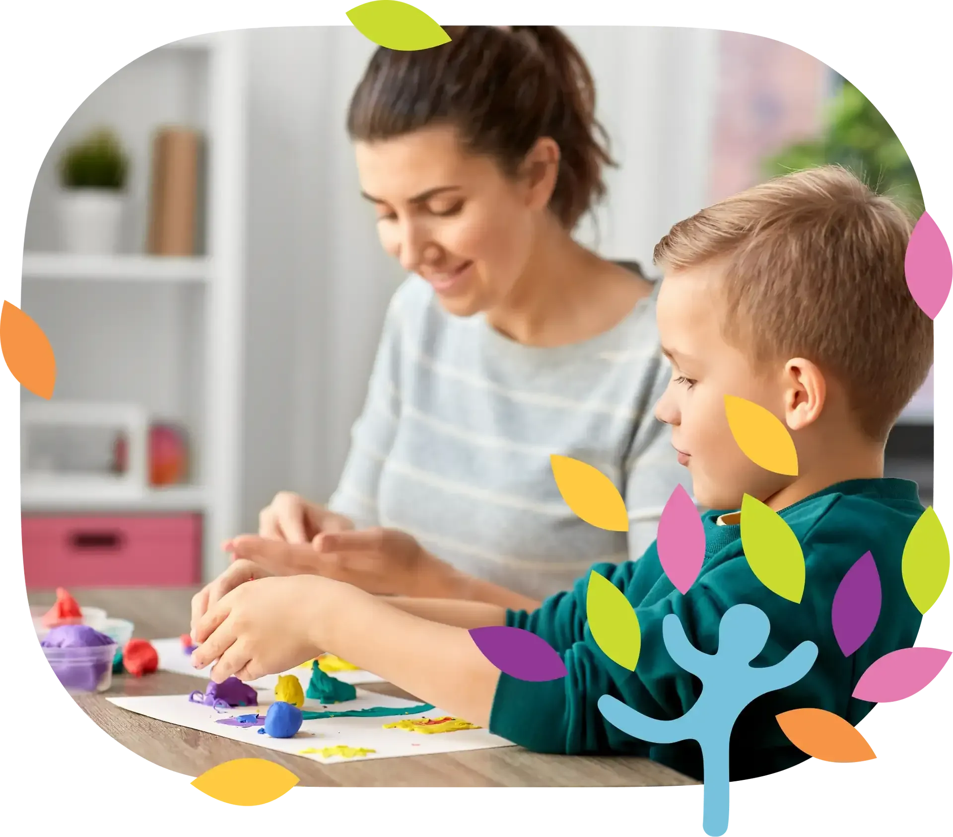 A person and a child sit at a table, smiling while playing with colorful modeling clay on paper in a bright room.