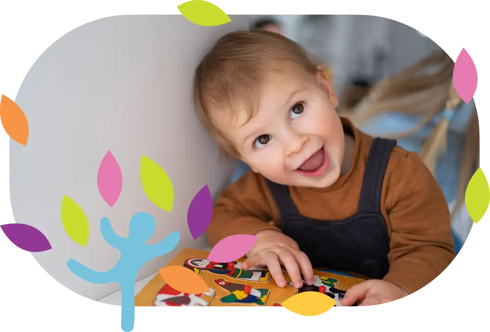 A smiling child leans against a wall while playing with a colorful wooden puzzle, framed by stylized decorative leaves.