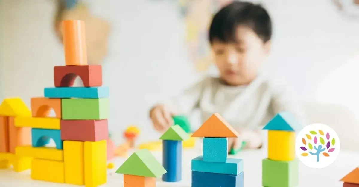A young child playing with colorful wooden building blocks in a bright indoor setting.