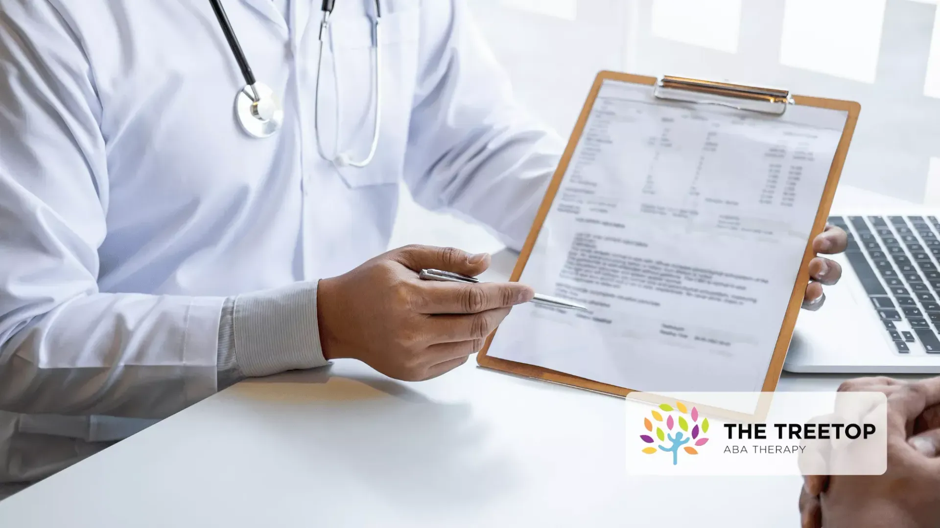 A healthcare professional in a white coat points to a document on a clipboard during a consultation.