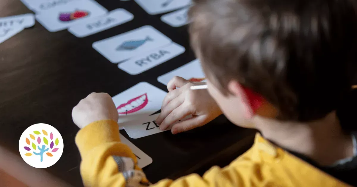 A person in a yellow shirt uses flashcards with pictures and text to practice reading or speech therapy.