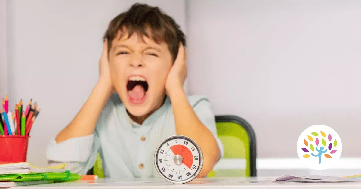 A person sitting at a desk with hands over ears, mouth open in a shout, with a visual timer set in front of them.