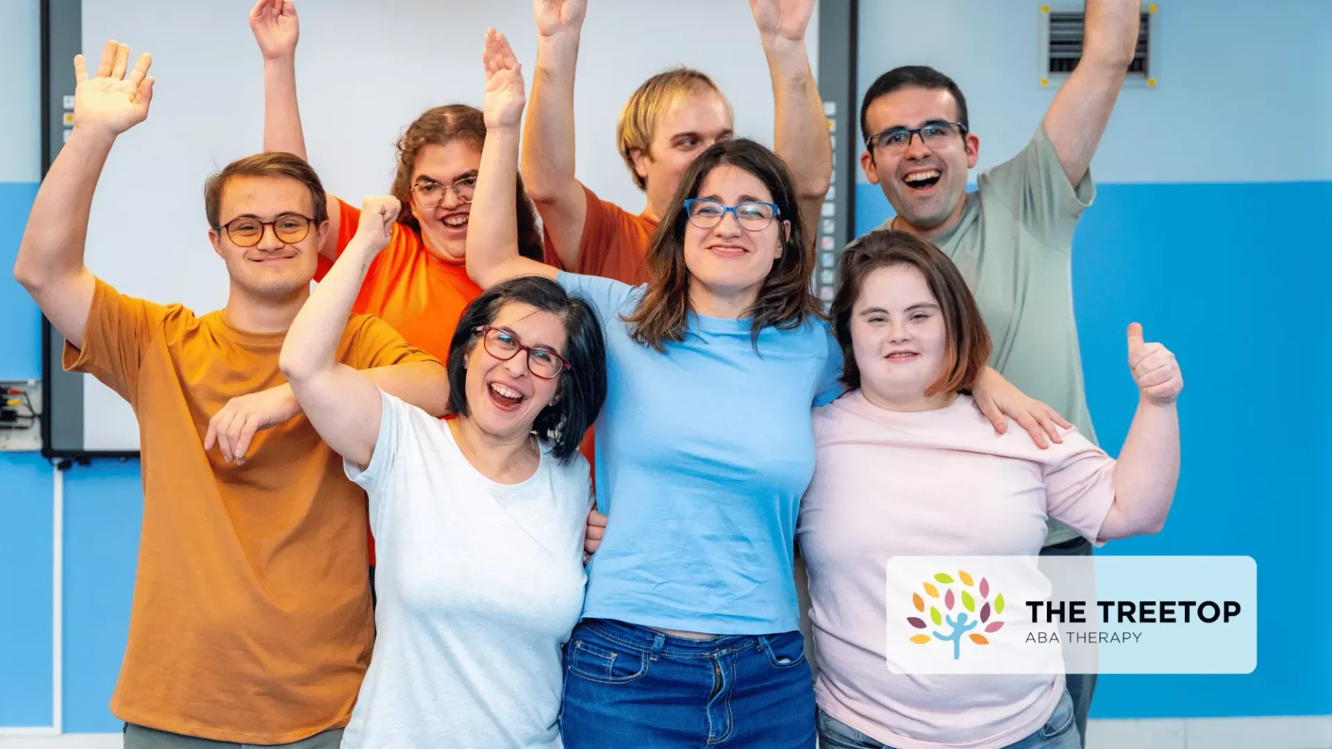 A group of six people smiling and cheering in front of a whiteboard with a Treetop Academy logo in the corner.
