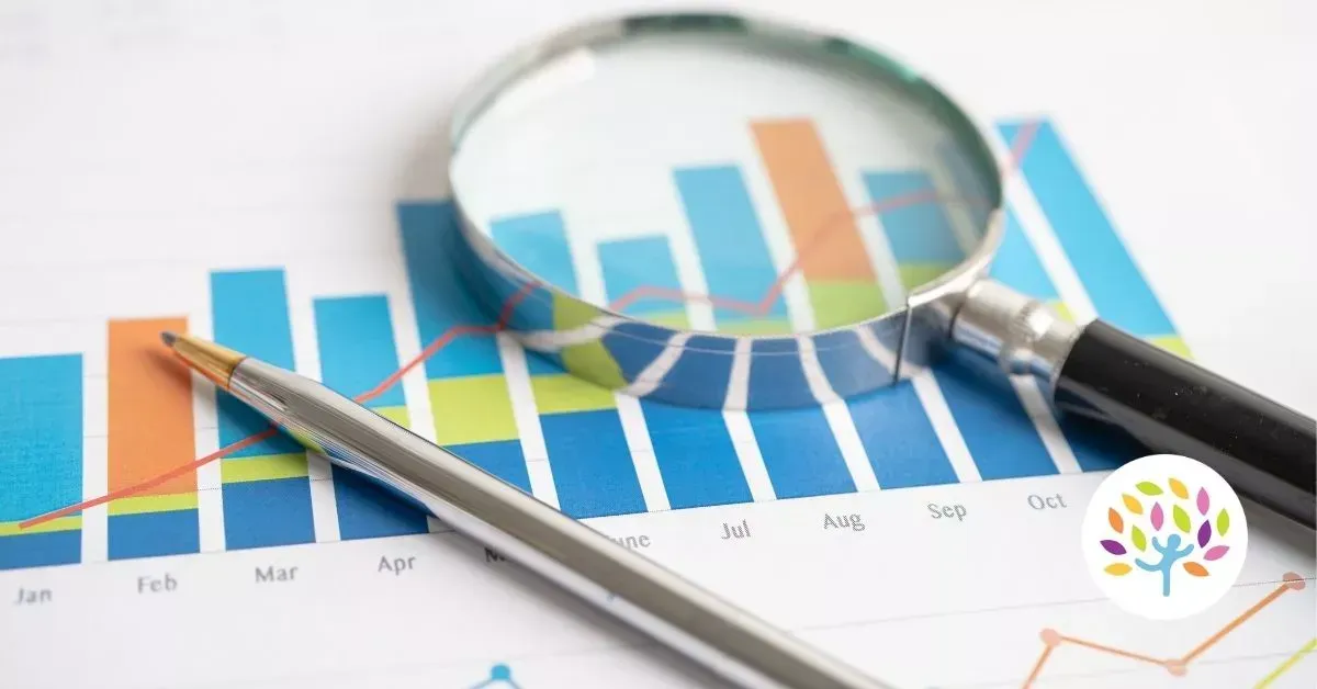 Magnifying glass and pencil over colorful bar charts and line graphs on a desk