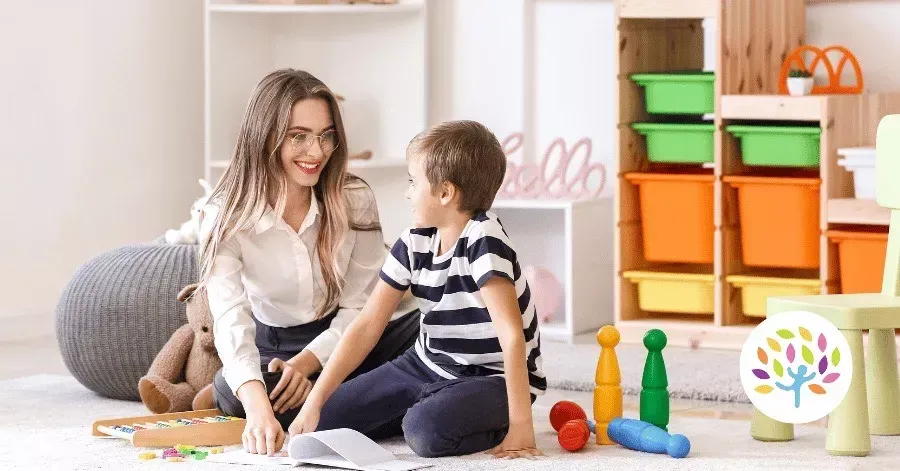 Adult and child sitting on the floor playing with colorful blocks in a bright playroom