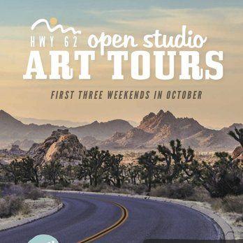 Two people hike on a desert trail, surrounded by rocks and Joshua trees, wearing hats and carrying packs.