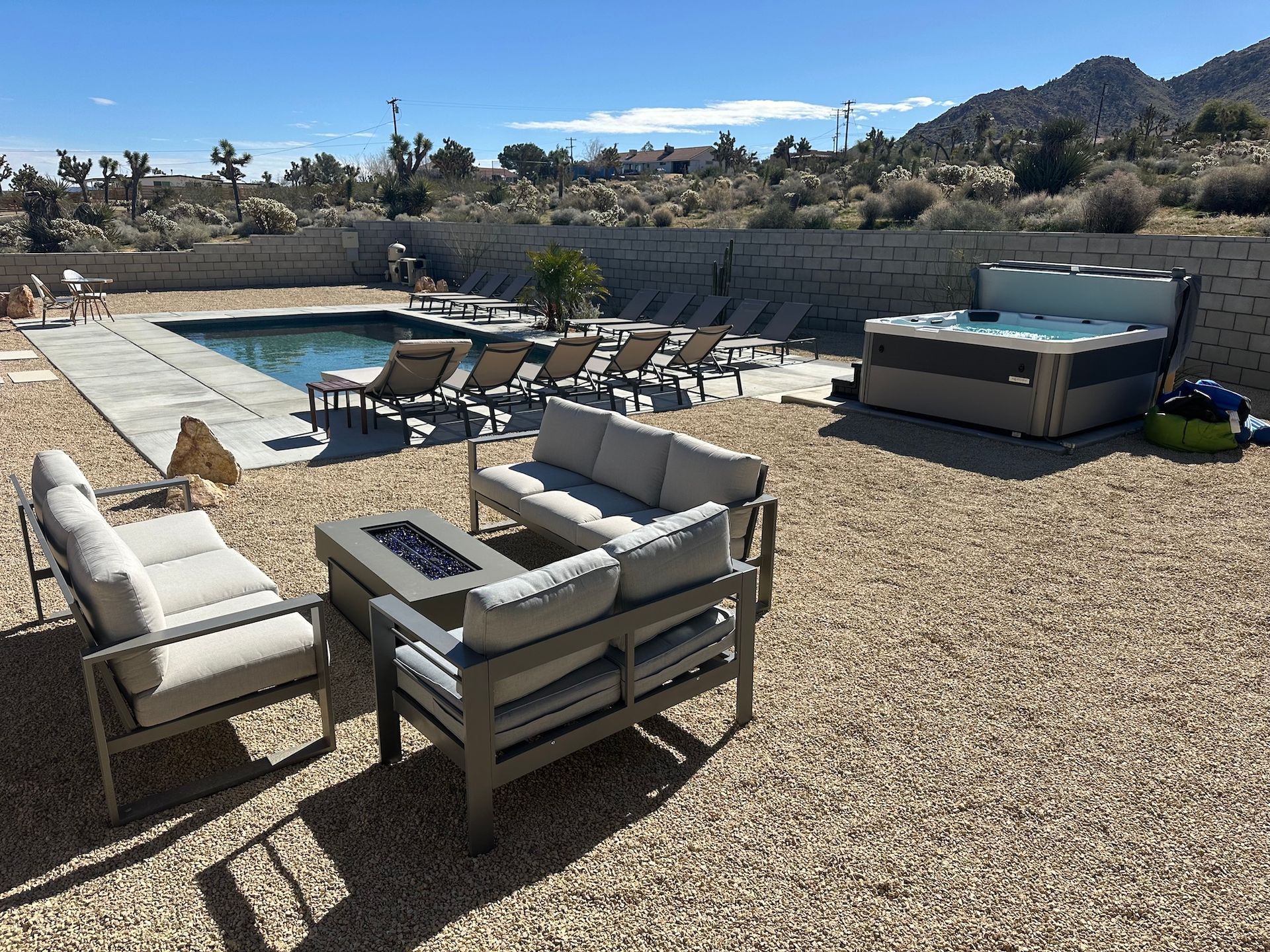 Outdoor space with pool, hot tub, lounge chairs, and seating area in a desert landscape.