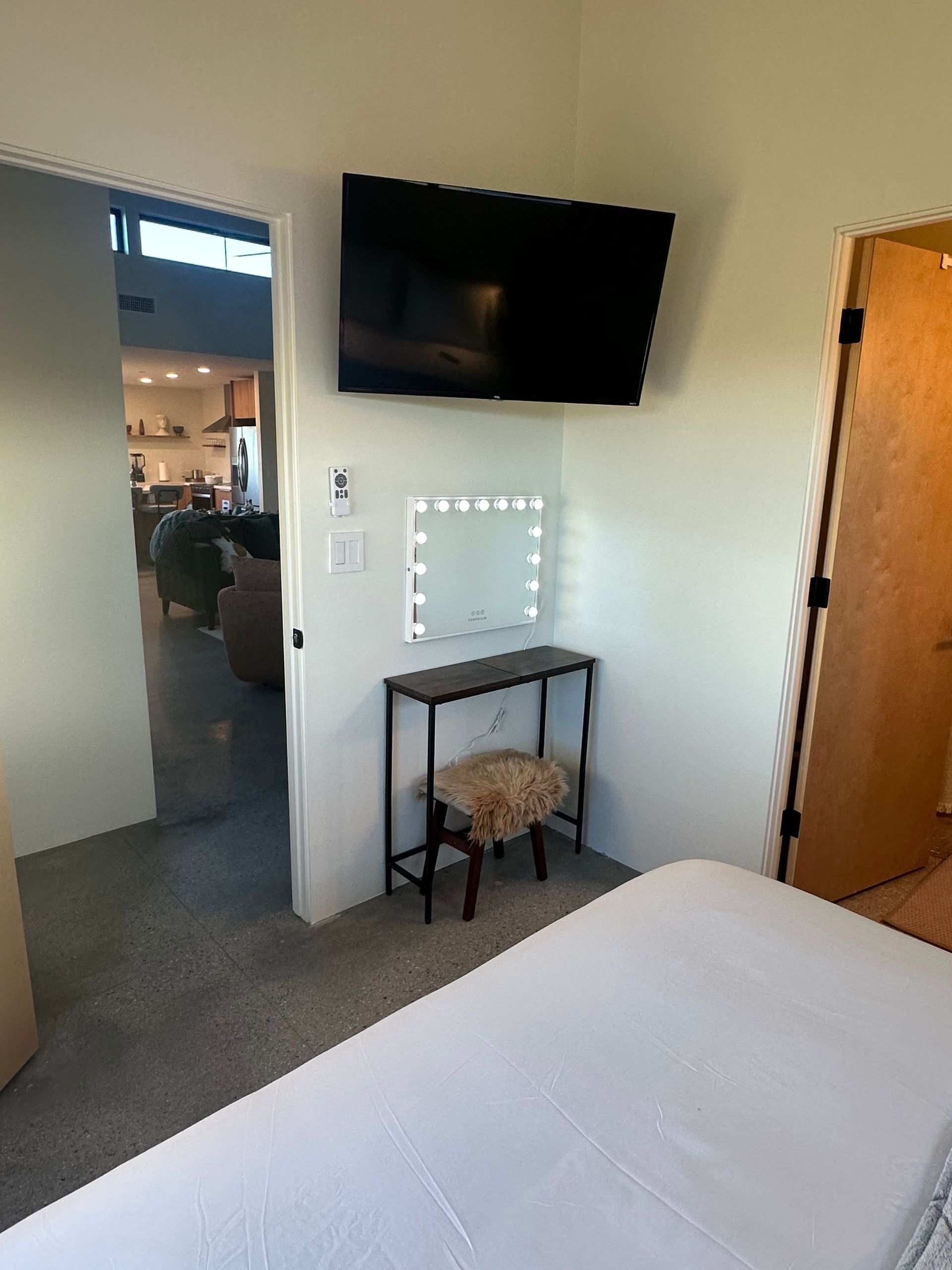 Bedroom corner with TV, vanity, and open doorway to living area.