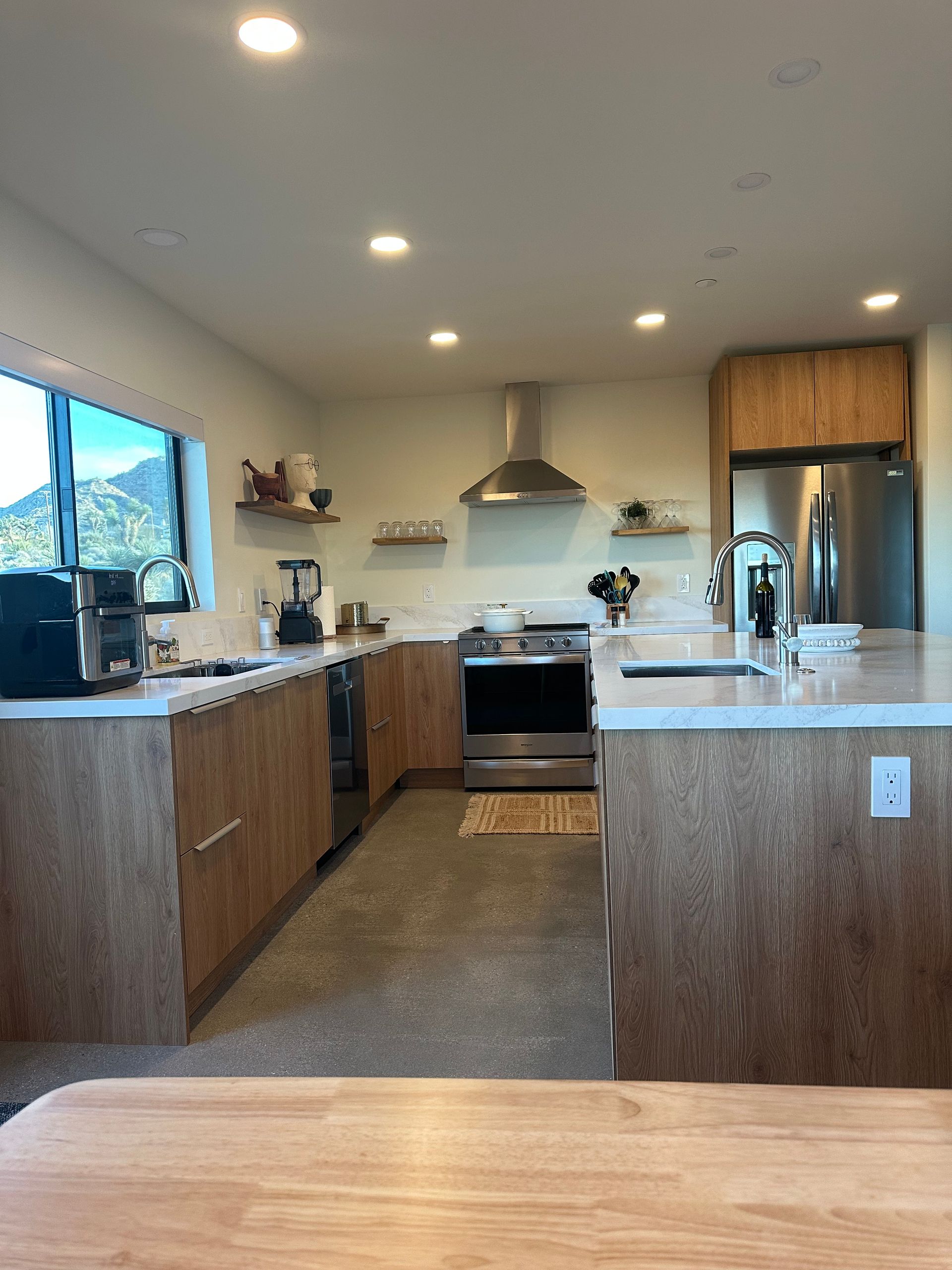 Modern kitchen with light wood cabinets, stainless steel appliances, and a central island.
