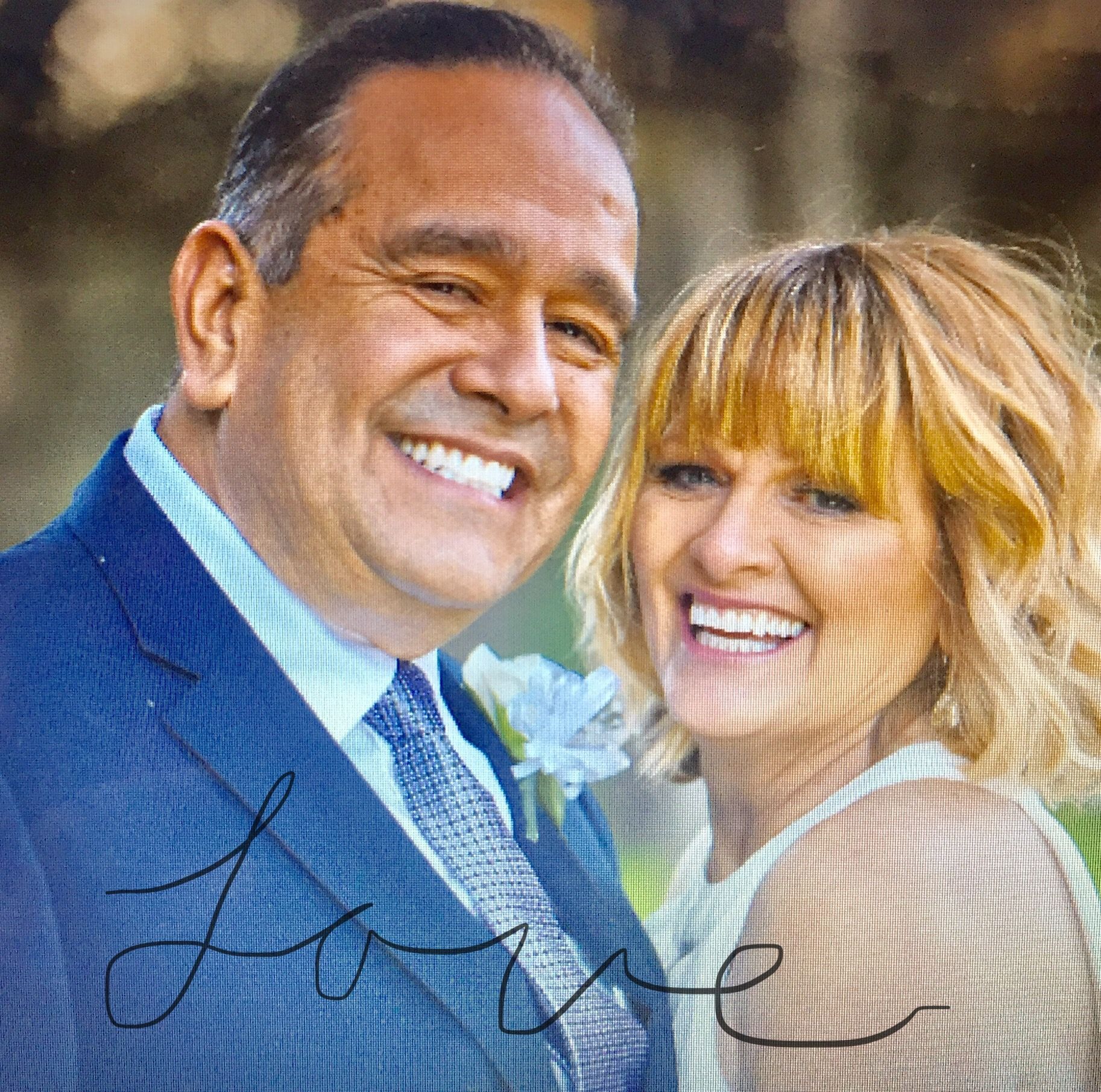 A smiling couple poses for a photo, with the cursive word 