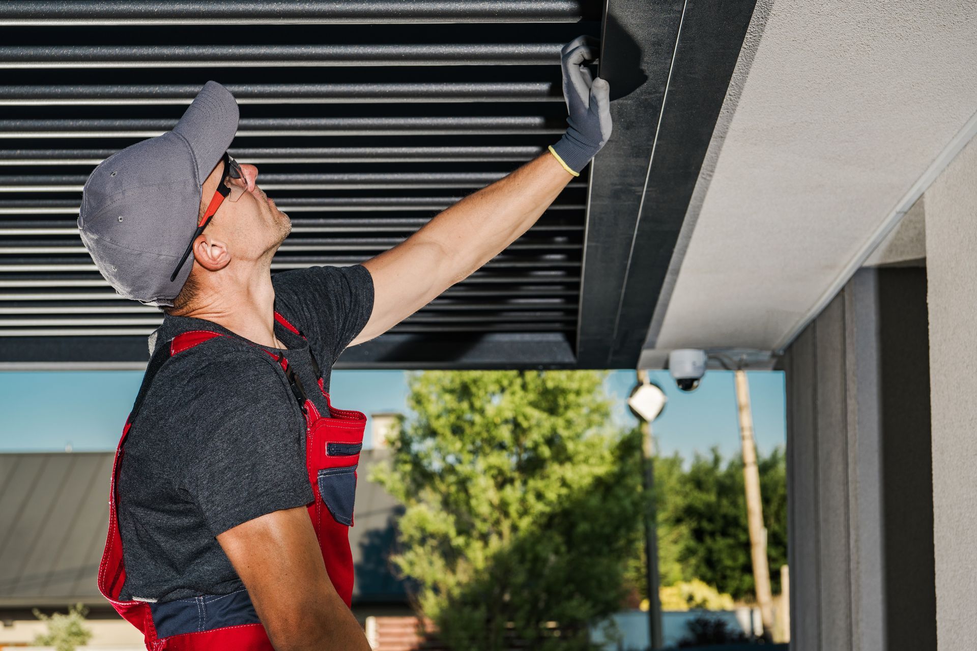 A worker inspecting metal pergola structure on home exterior
