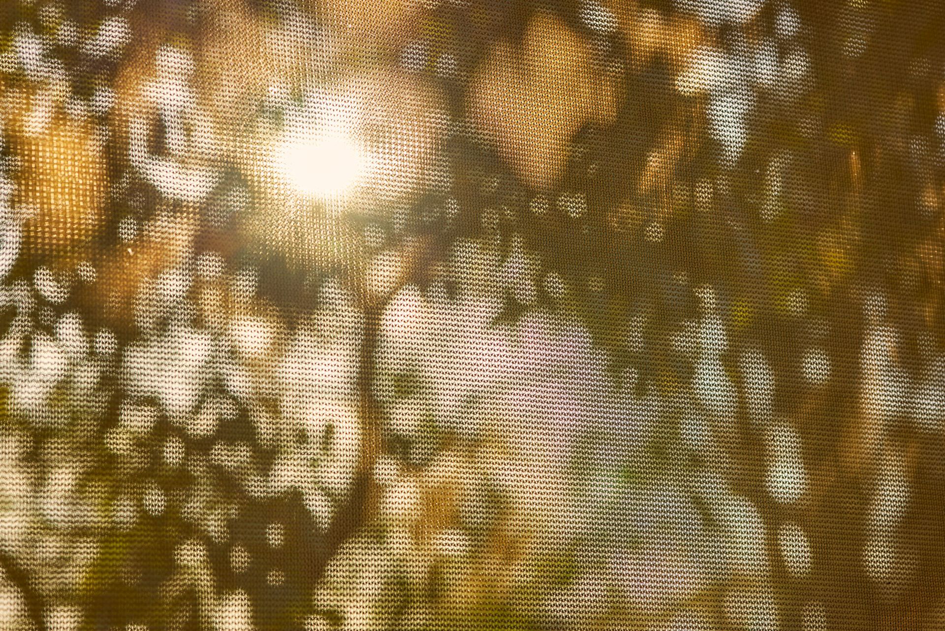 A close up of a knitted fabric with the sun shining through it.