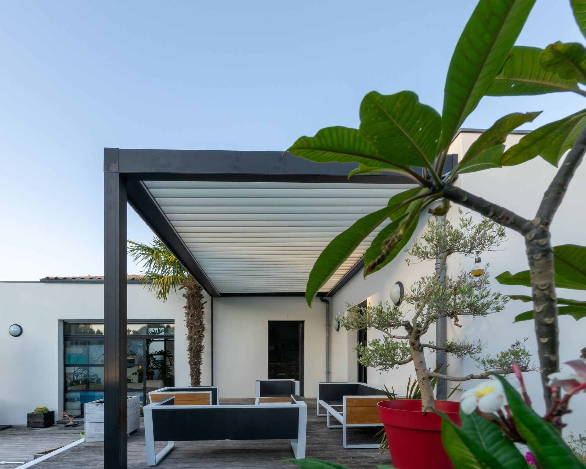 A pergola with a couch and chairs underneath it