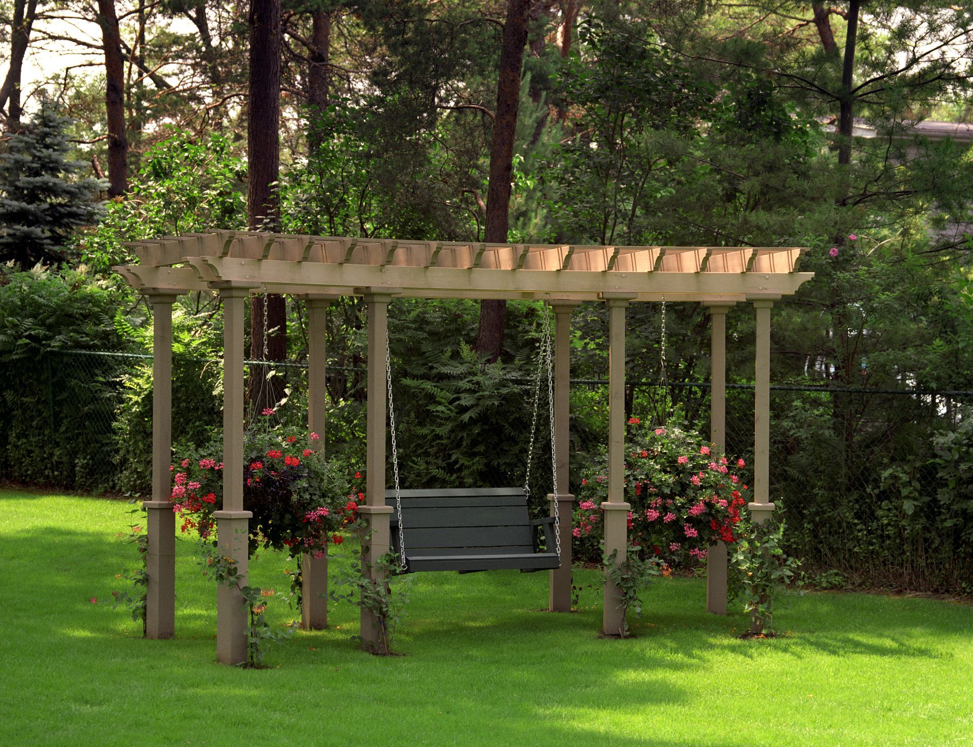 Wooden pergola with flowers to the sides, with a wooden swing below it.