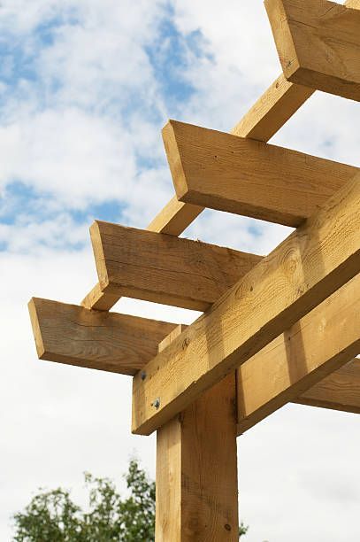 Close-up shot of the corner of a wooden pergola against the blue sky.