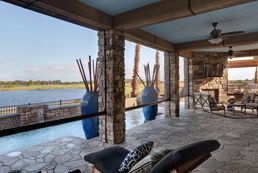 A patio with a view of a lake and a swimming pool.