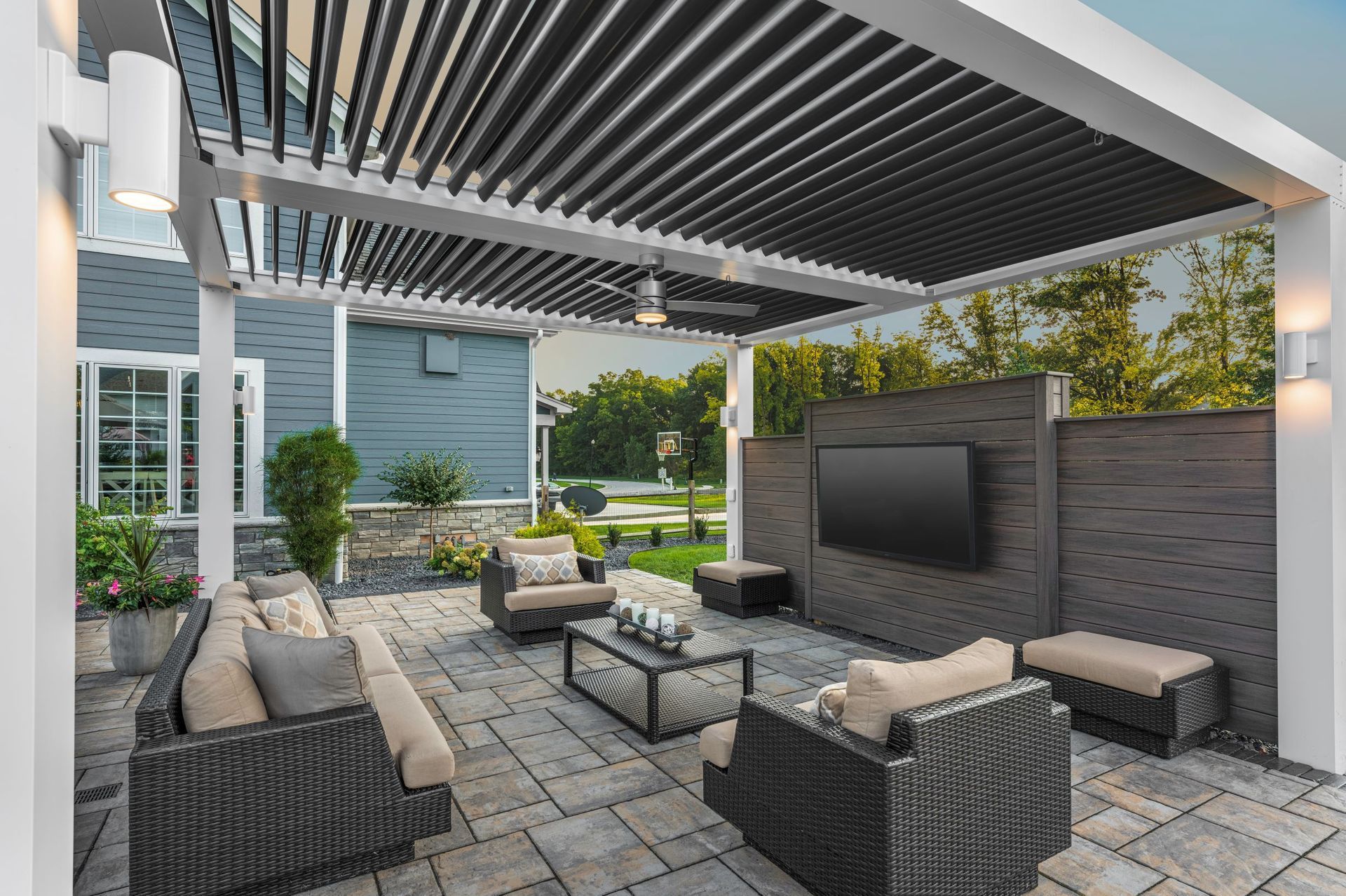 A patio with furniture and a television under a pergola.