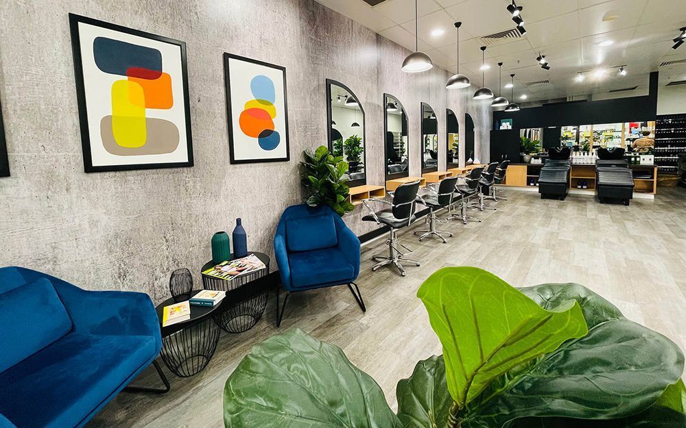 A Salon with A Couch , Chairs , Mirrors and A Plant — Statix Hair Yeppoon in Rockhampton City, QLD
