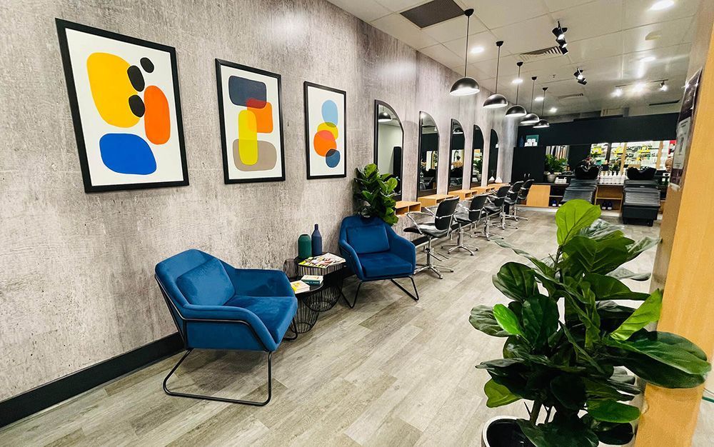 A Salon with Chairs , Tables , Plants and Paintings on The Wall — Statix Hair Yeppoon in Blackwater, QLD