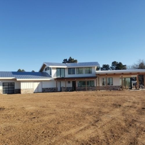 A large house is sitting in the middle of a dirt field.