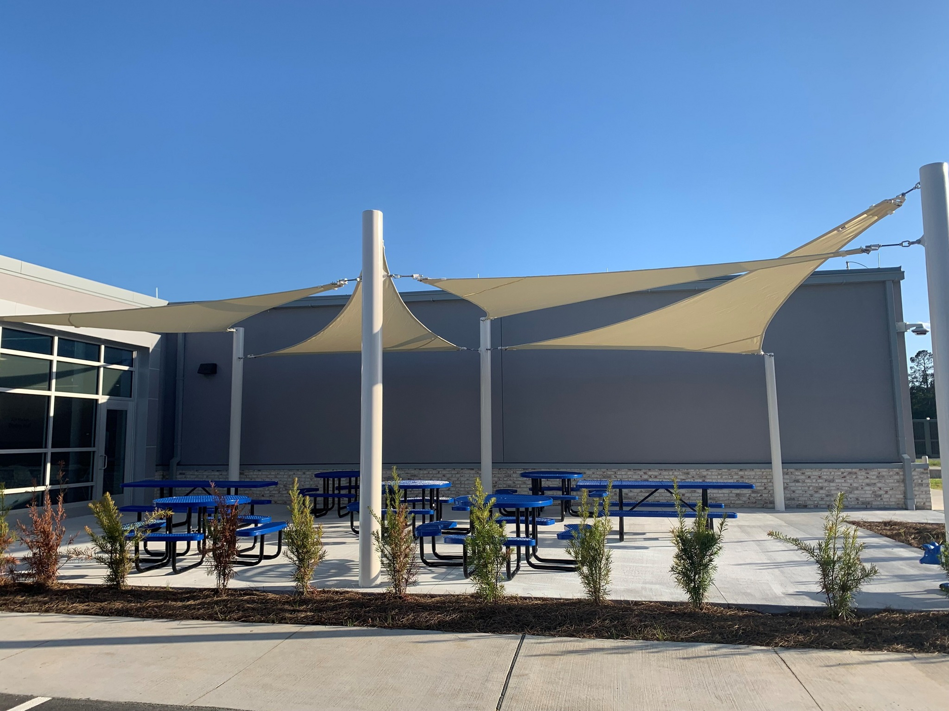 A row of picnic tables under umbrellas in front of a building