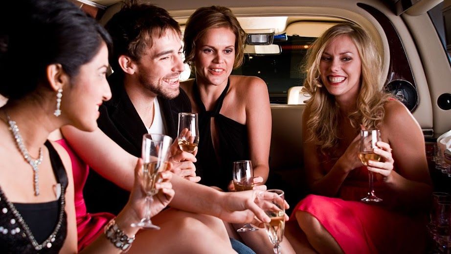 A group of people are sitting in a limousine toasting with champagne glasses.