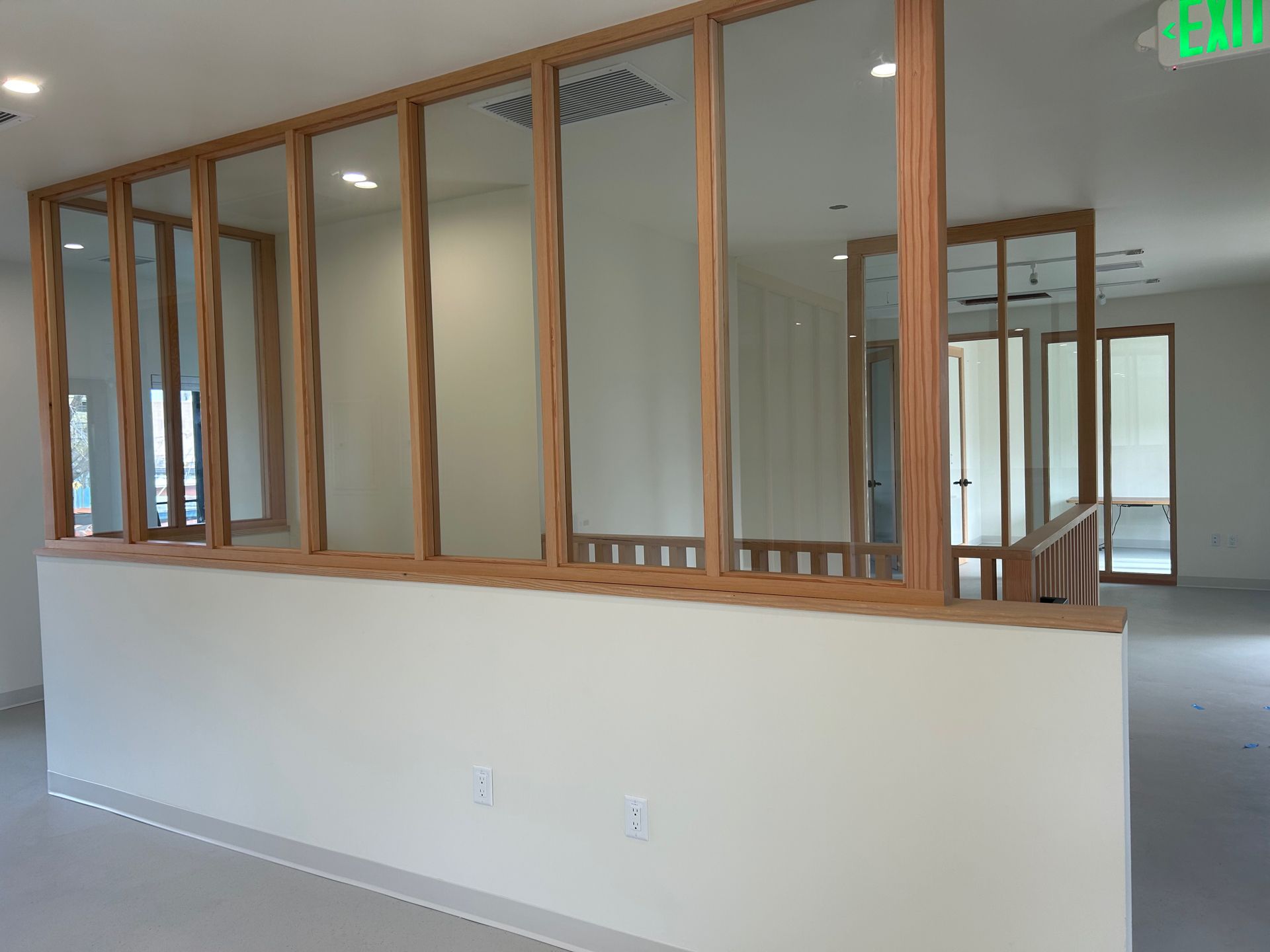 Interior with wooden framed windows on a white wall, leading to another room with door.