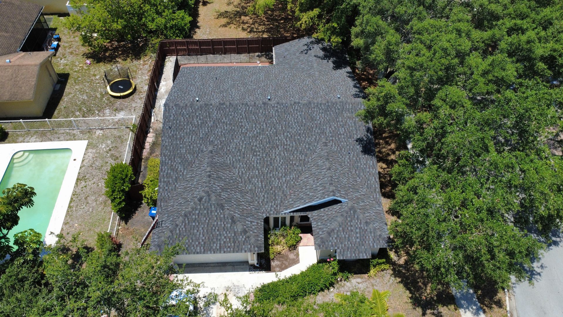 Overhead view of a brown roof with two skylights, pipes, and ridges.