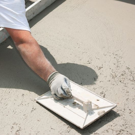 Palma Construction LLC | A man is using a trowel on a concrete surface
