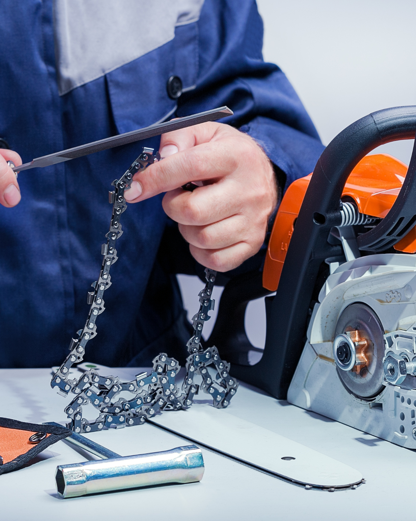 A man is sharpening a chainsaw with a pair of scissors