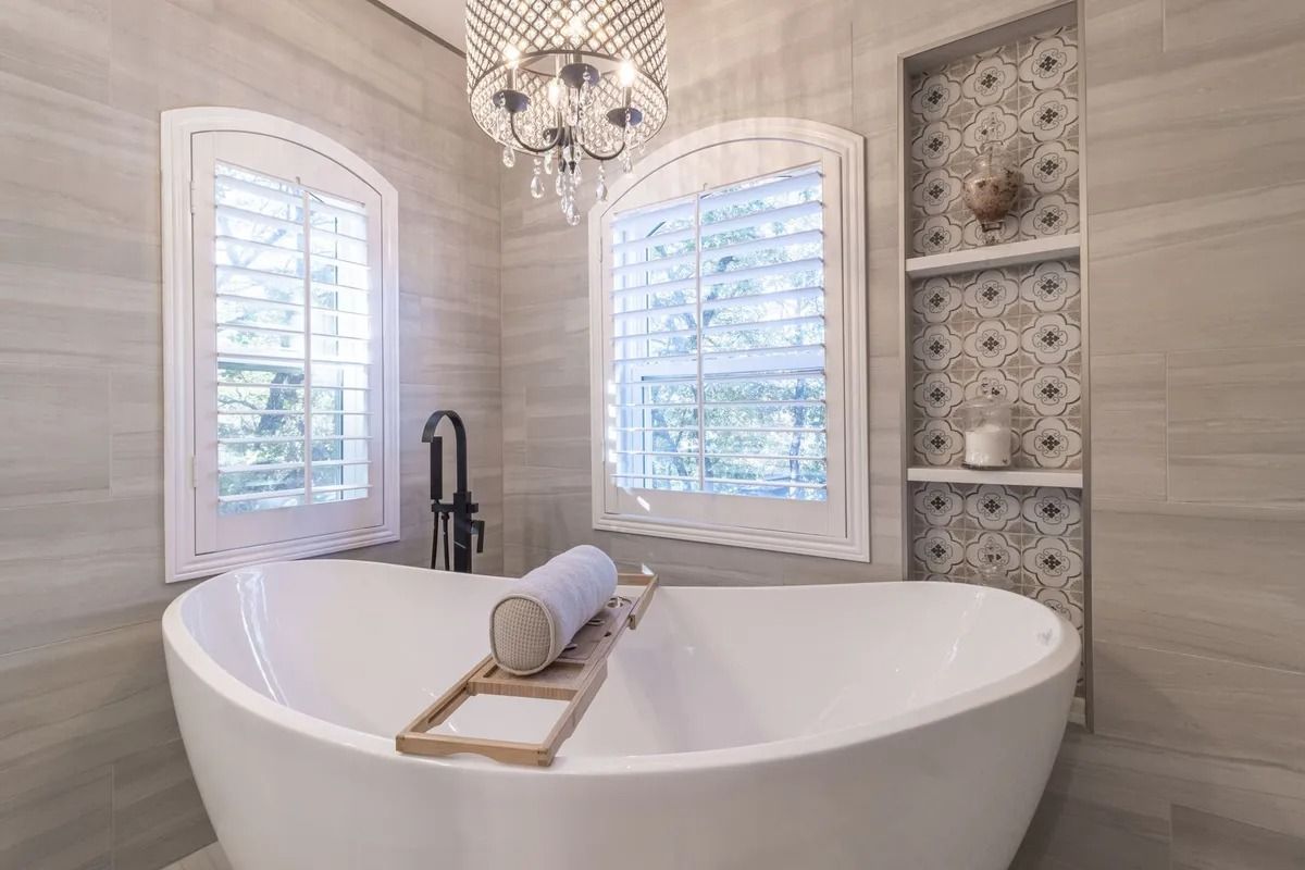 Elegant bathroom with a freestanding tub, chandelier, and patterned tile shelves