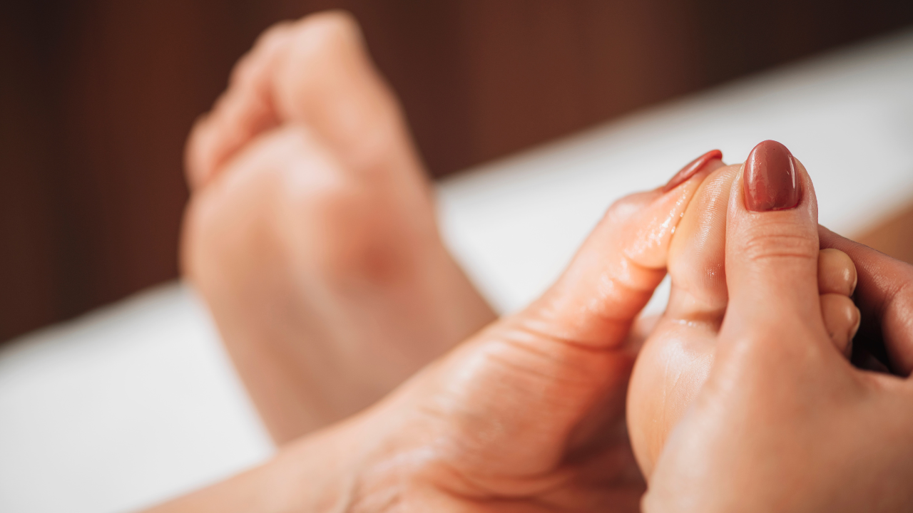 Hands massaging a foot, likely in a spa or relaxing setting.
