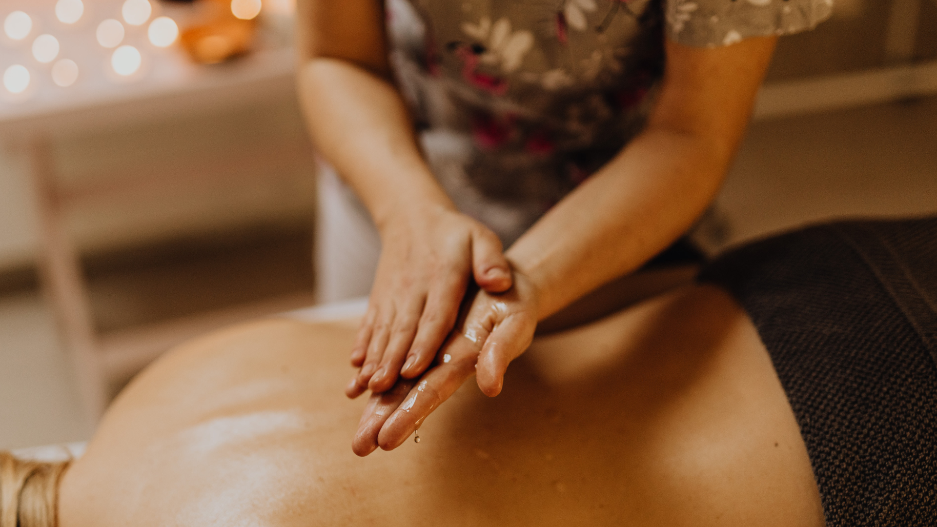 Hands applying oil to someone's back during a massage.