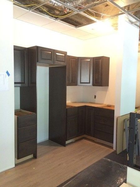 A kitchen under construction with dark cabinets and a refrigerator