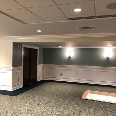 A large empty room with a carpeted floor and a ceiling.