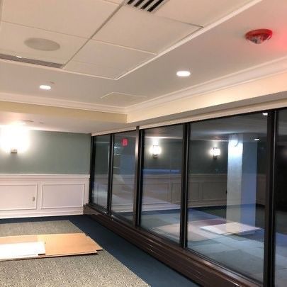 A large room with a lot of windows and a fire alarm on the ceiling.