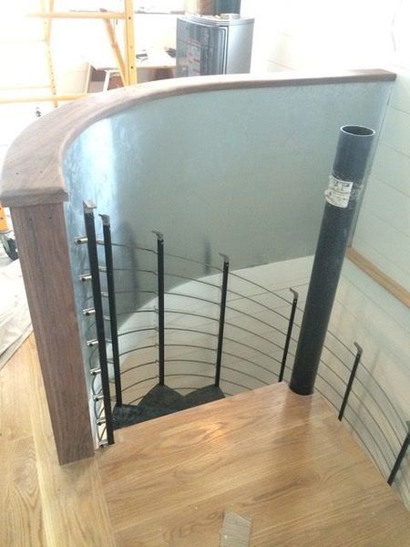 A spiral staircase with a wooden railing and a metal railing