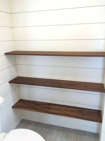 A bathroom with wooden shelves and a toilet.