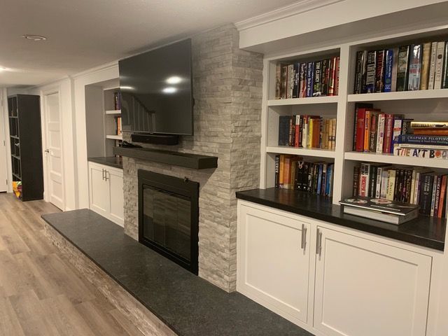 A living room with a fireplace , bookshelves , and a flat screen tv.
