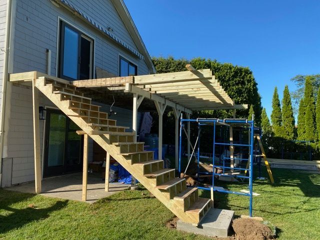 A wooden deck is being built in the backyard of a house.