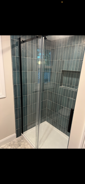 A bathroom with a walk in shower with a glass door.