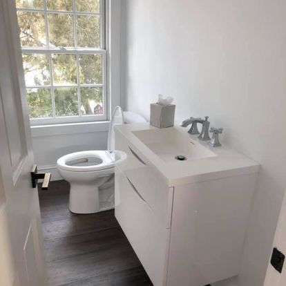 A bathroom with a toilet , sink , and window.