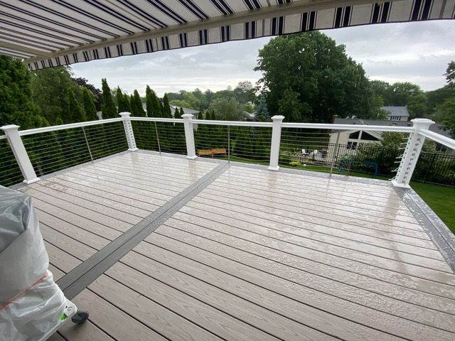 A wooden deck with a white railing and a striped awning.