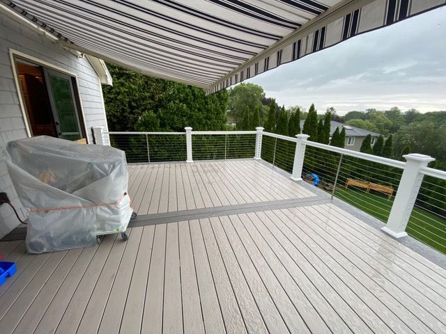 A deck with a striped awning and a grill on it
